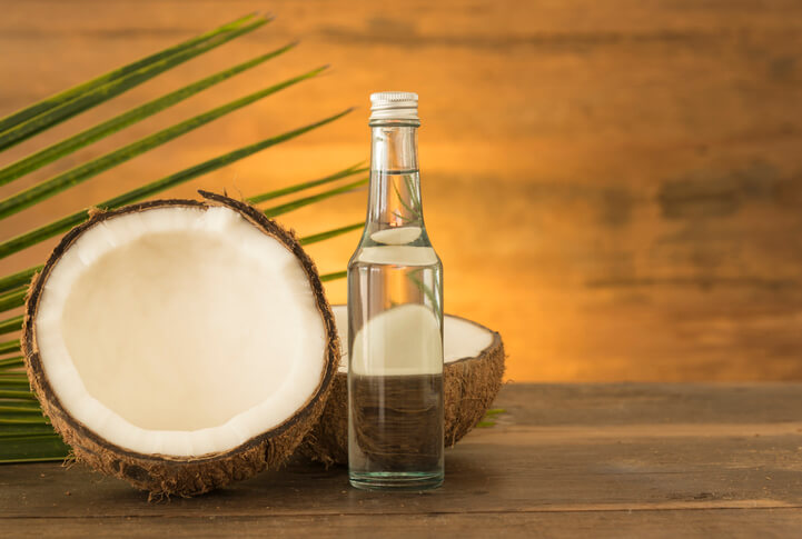 coconut oil and fresh coconuts on wooden table.